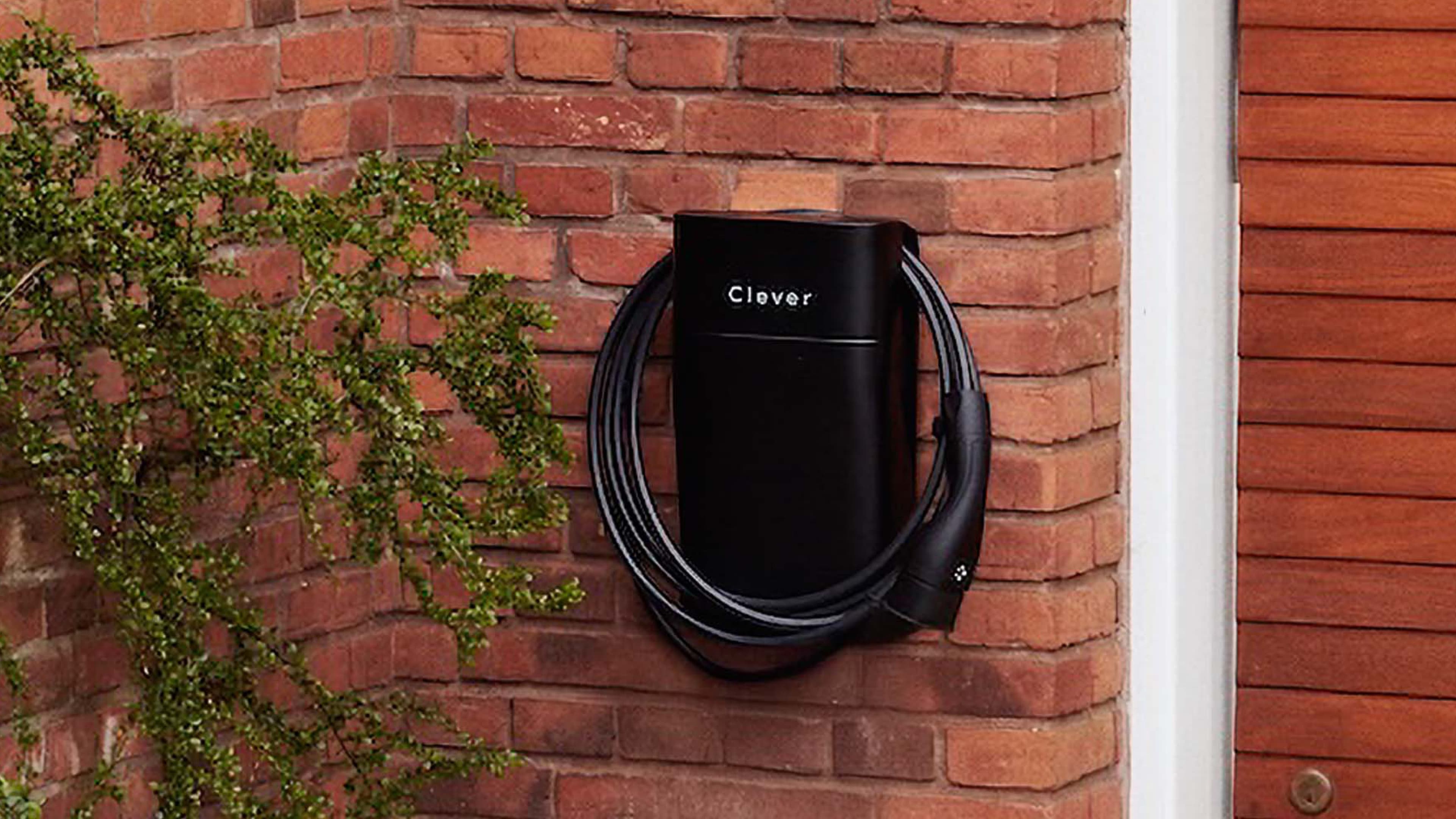 Clever ladeboks og kabel ophængt på en rød murstensmur, og en plante der kravler opad væggen.