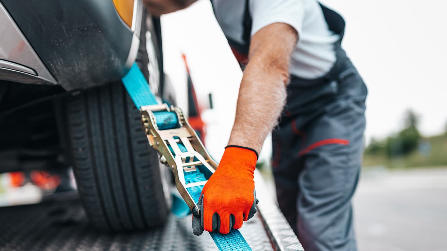 Vejhjælps-medarbejder spænder bil på lad